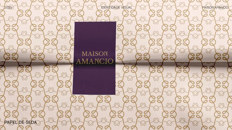 Papel de seda com padronagem do símbolo da Maison Amancio e etiqueta roxa com o logotipo.