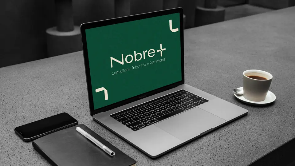 Notebook sobre a mesa exibindo o logotipo da Nobre Mais em tela verde.