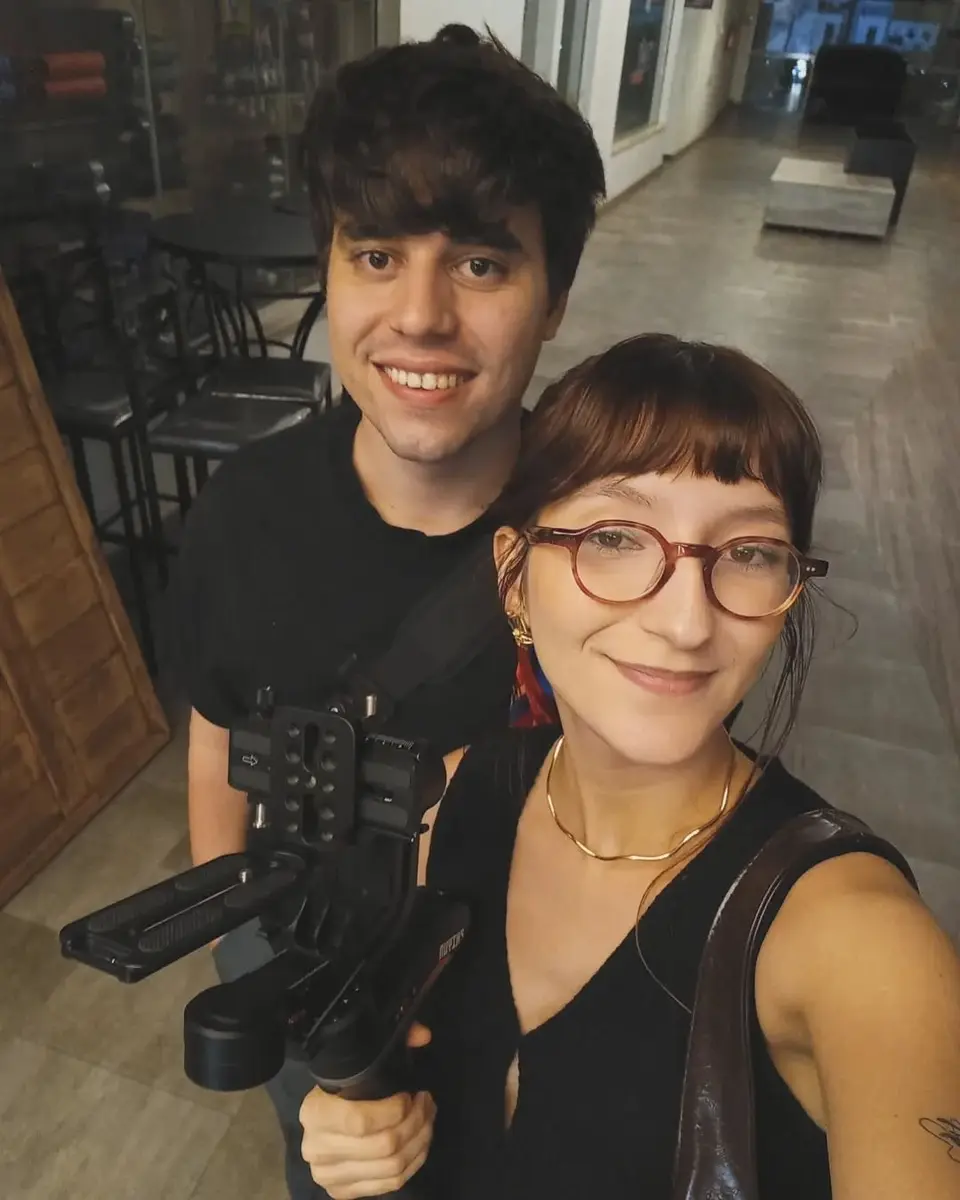 Victor Arias e Mylena Leite, fundadores da WGT Studio, sorrindo lado a lado numa selfie; Victor segura um estabilizador de câmera.